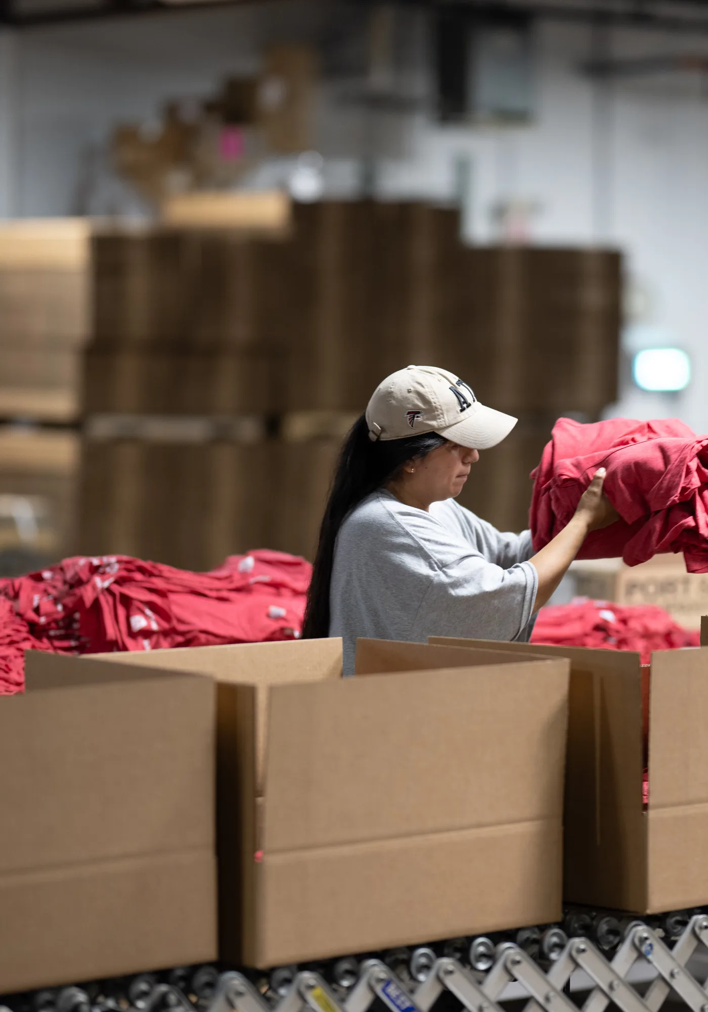 Team member picking folded shirts from stacks at the pack tables